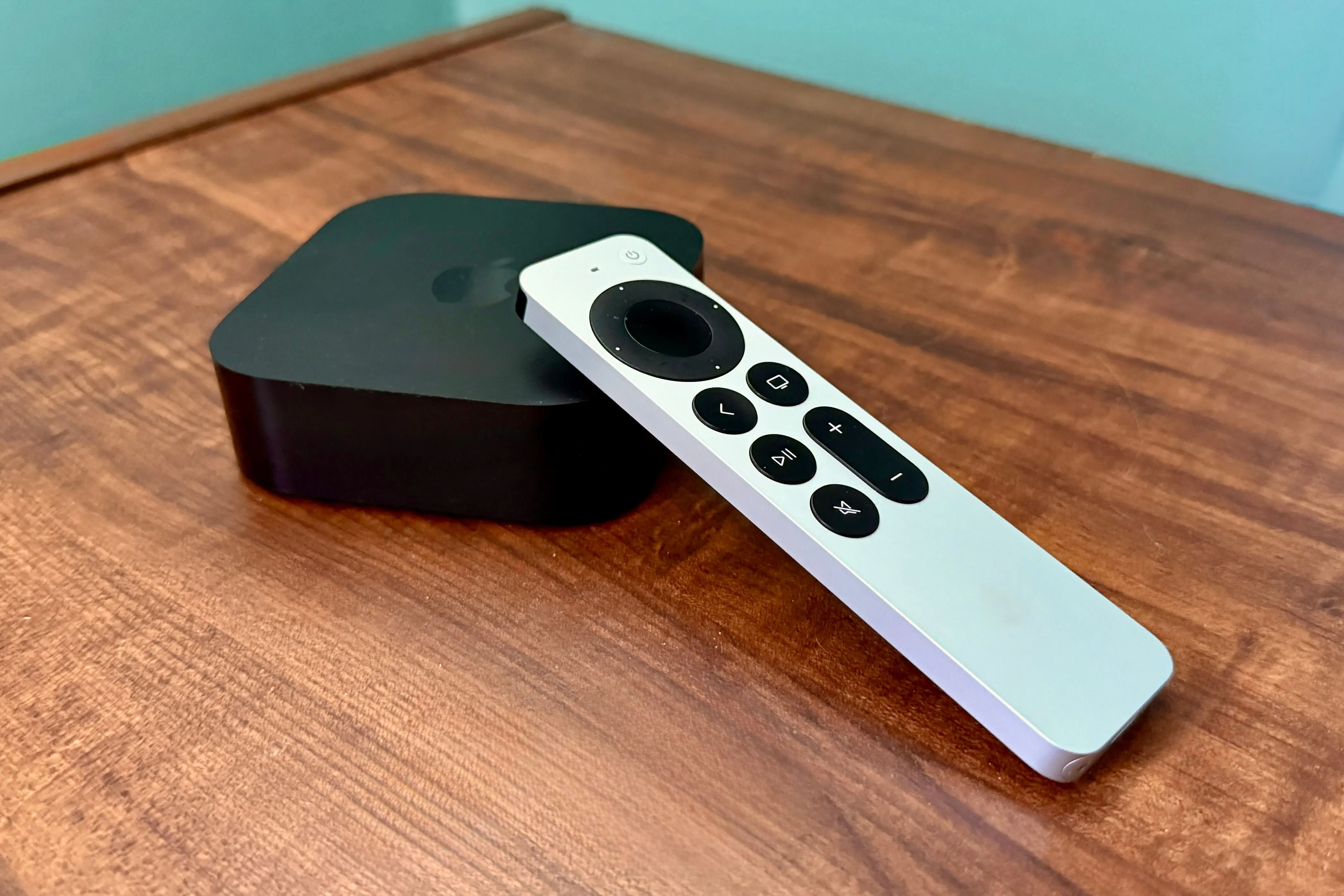 Apple TV và điều khiển đặt trên bàn gỗ, biểu tượng cho khả năng giải trí đa dạng.