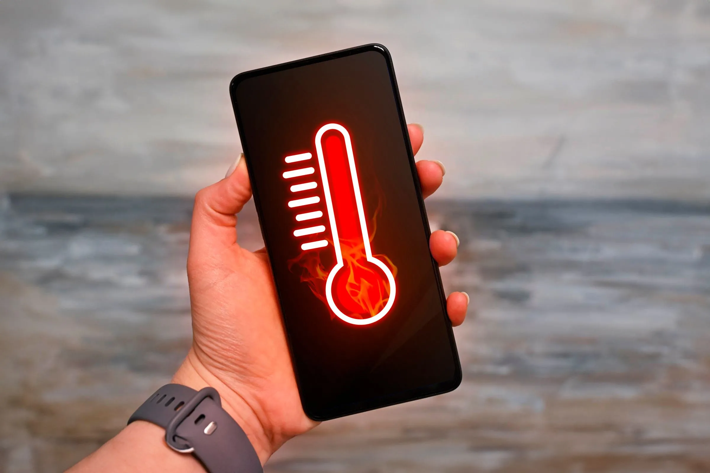 Bàn tay giữ smartphone kèm biểu tượng nhiệt kế và cảnh báo thiết bị đang quá nhiệt.