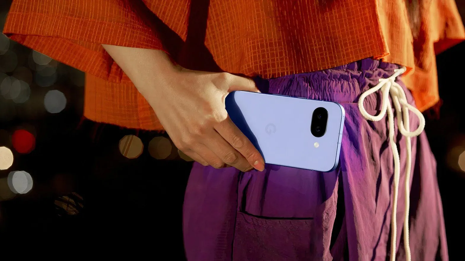 Cận cảnh một người phụ nữ đang cầm điện thoại Google Pixel 9a ở ngang eo, minh họa trải nghiệm sử dụng camera.
