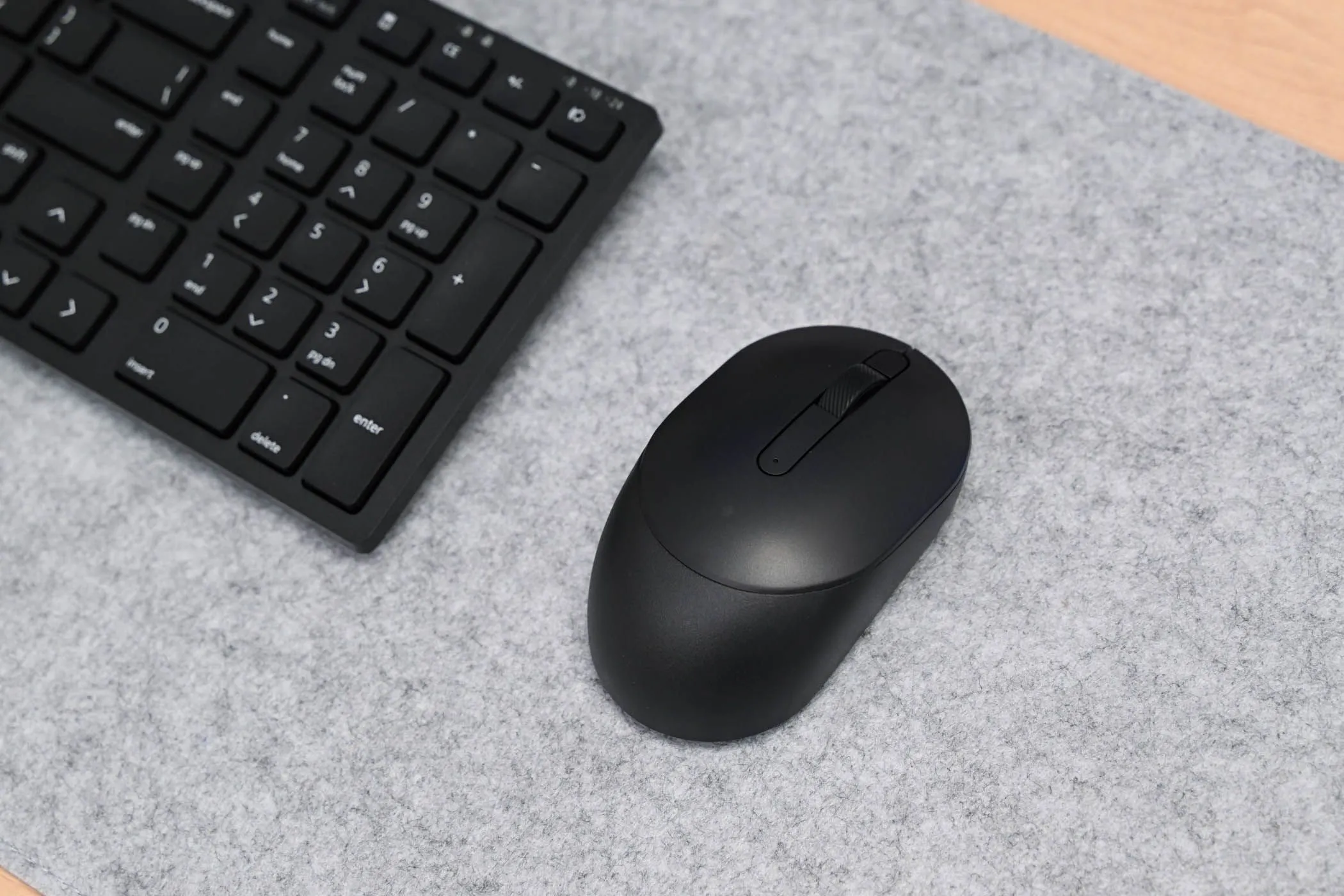 Chuột không dây Dell Silent Mouse màu đen đặt cạnh bàn phím Dell Silent Keyboard, kết hợp tạo thành bộ đôi làm việc hiệu quả với điện thoại.