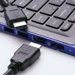 Hai đầu cáp HDMI gần cổng HDMI của laptop màu xanh hiện đại