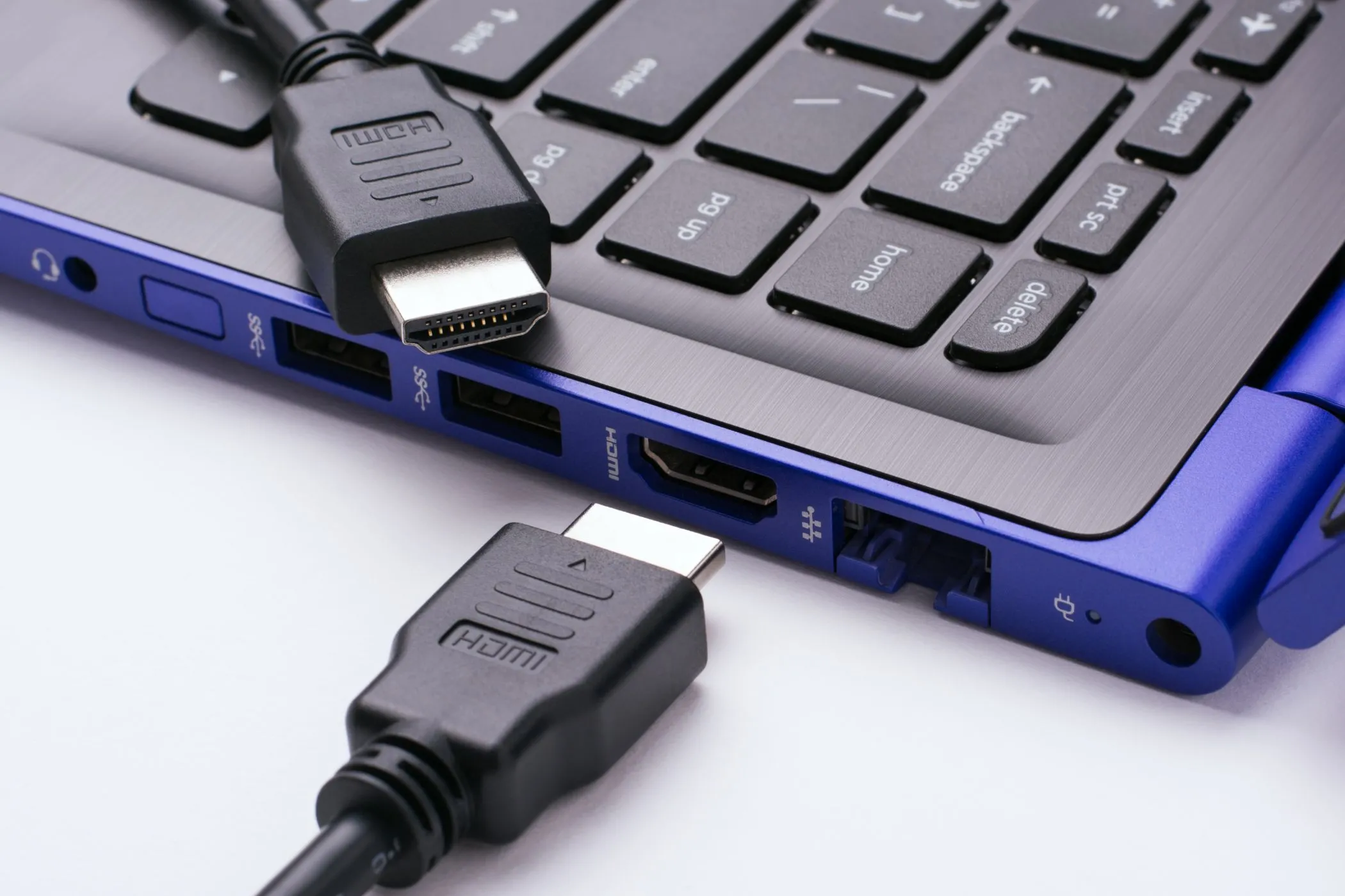 Hai đầu cáp HDMI gần cổng HDMI của laptop màu xanh hiện đại