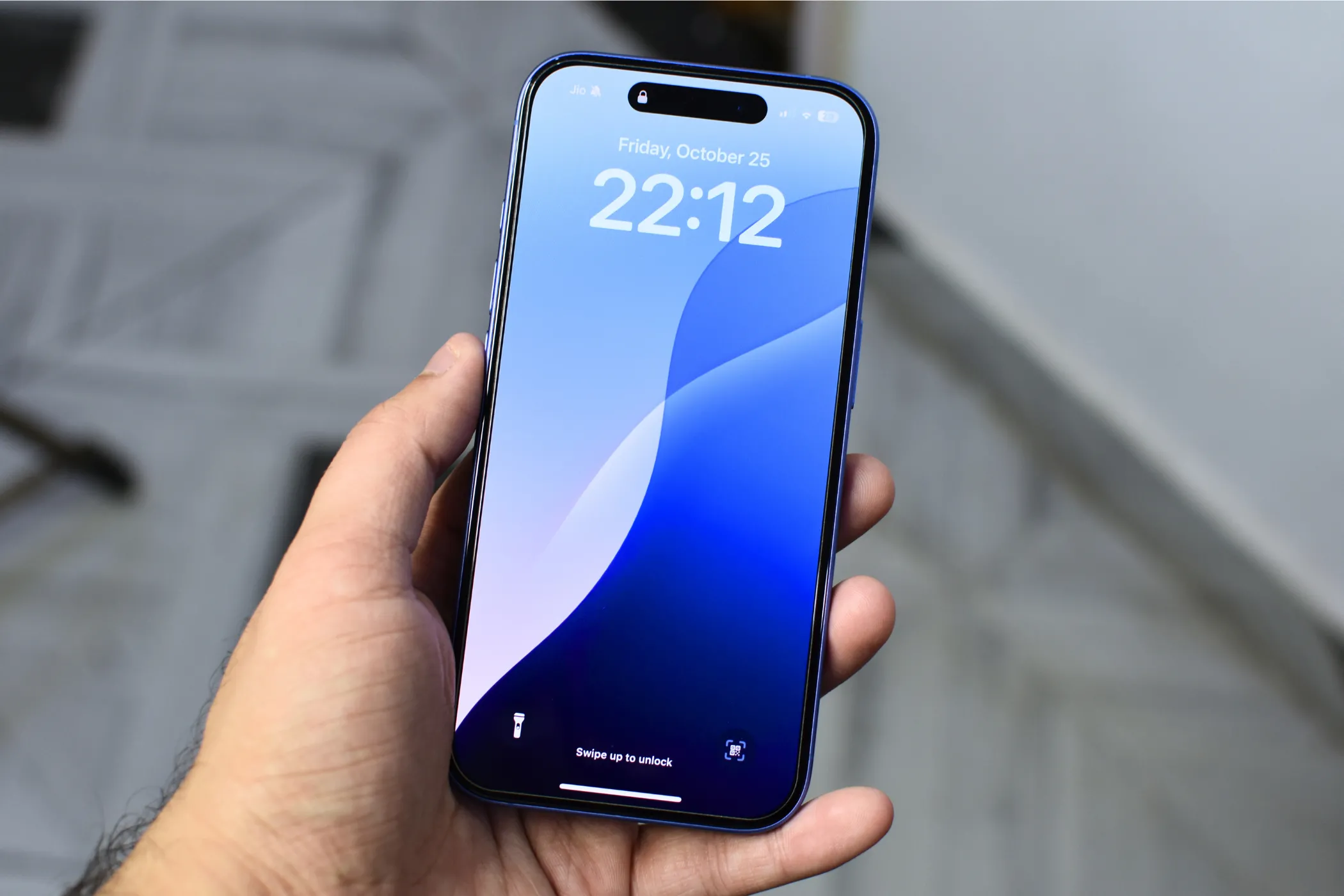 iPhone 16 được cầm trên tay, màn hình hiển thị hình nền màu xanh, minh họa trải nghiệm người dùng với các dòng iPhone.