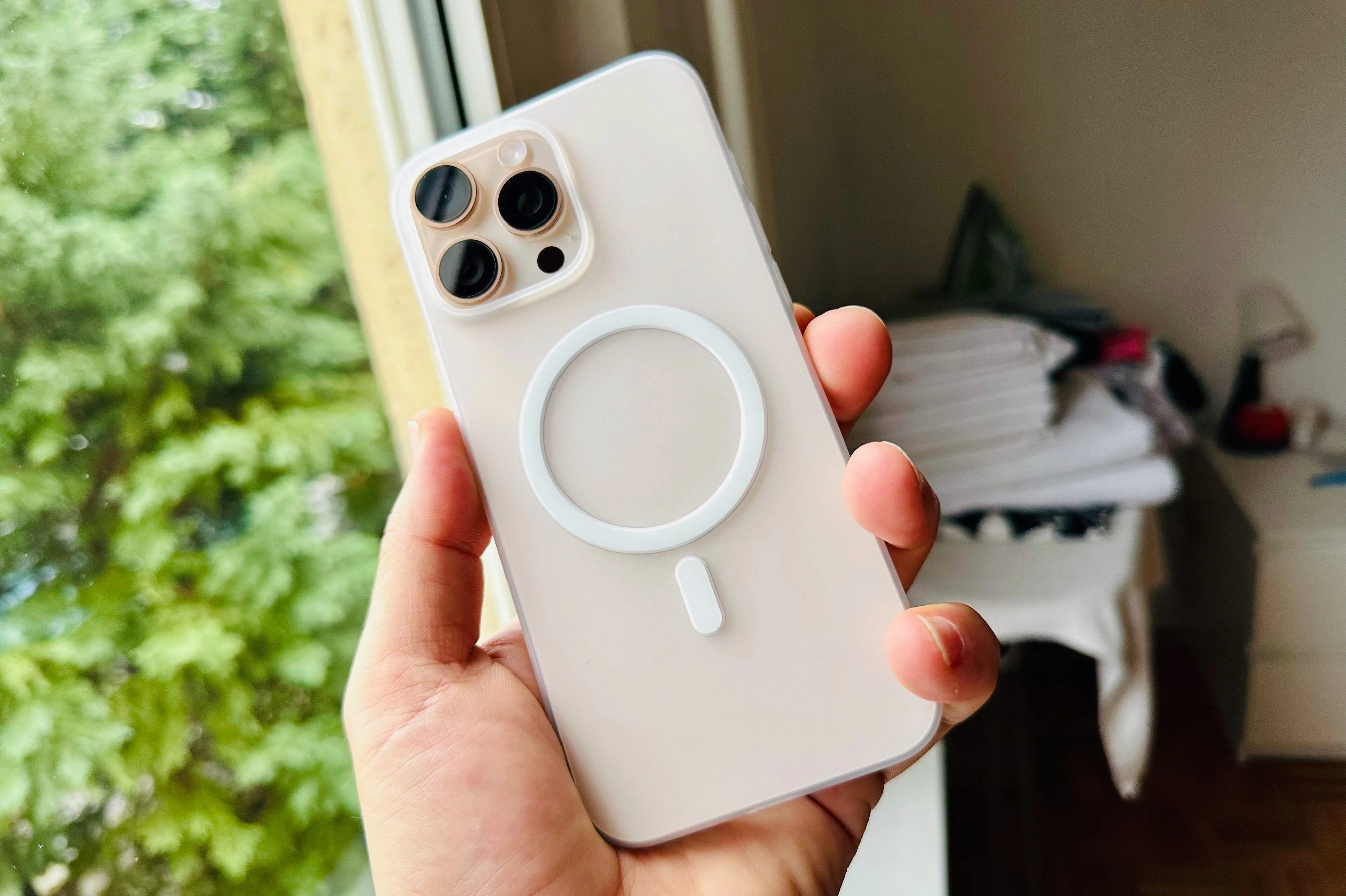 Mặt lưng iPhone 16 Pro Max màu titan sa mạc với cụm ba camera Pro, được bảo vệ bởi ốp MagSafe trong suốt.