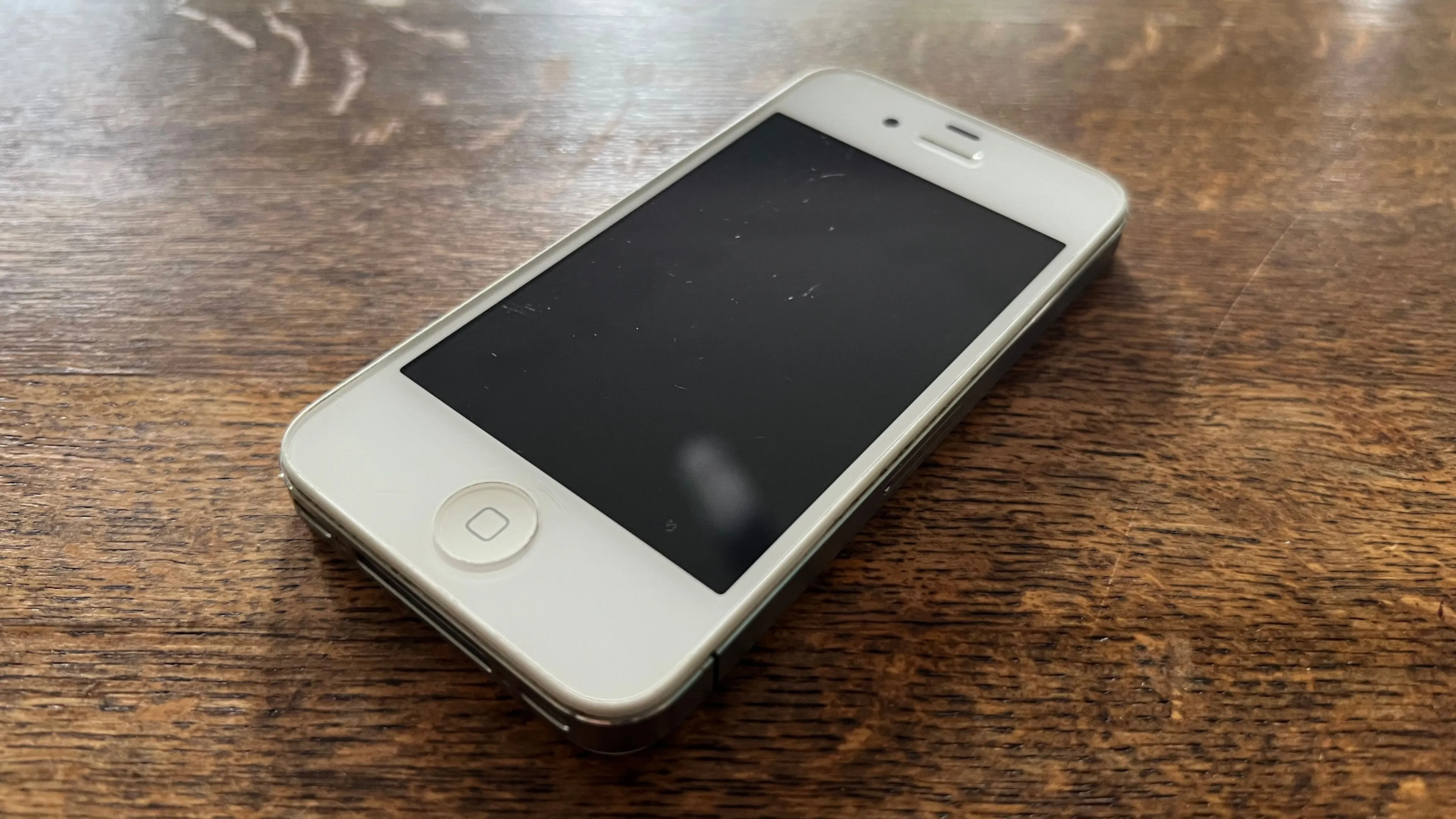Một chiếc iPhone 4S màu trắng trên mặt bàn.