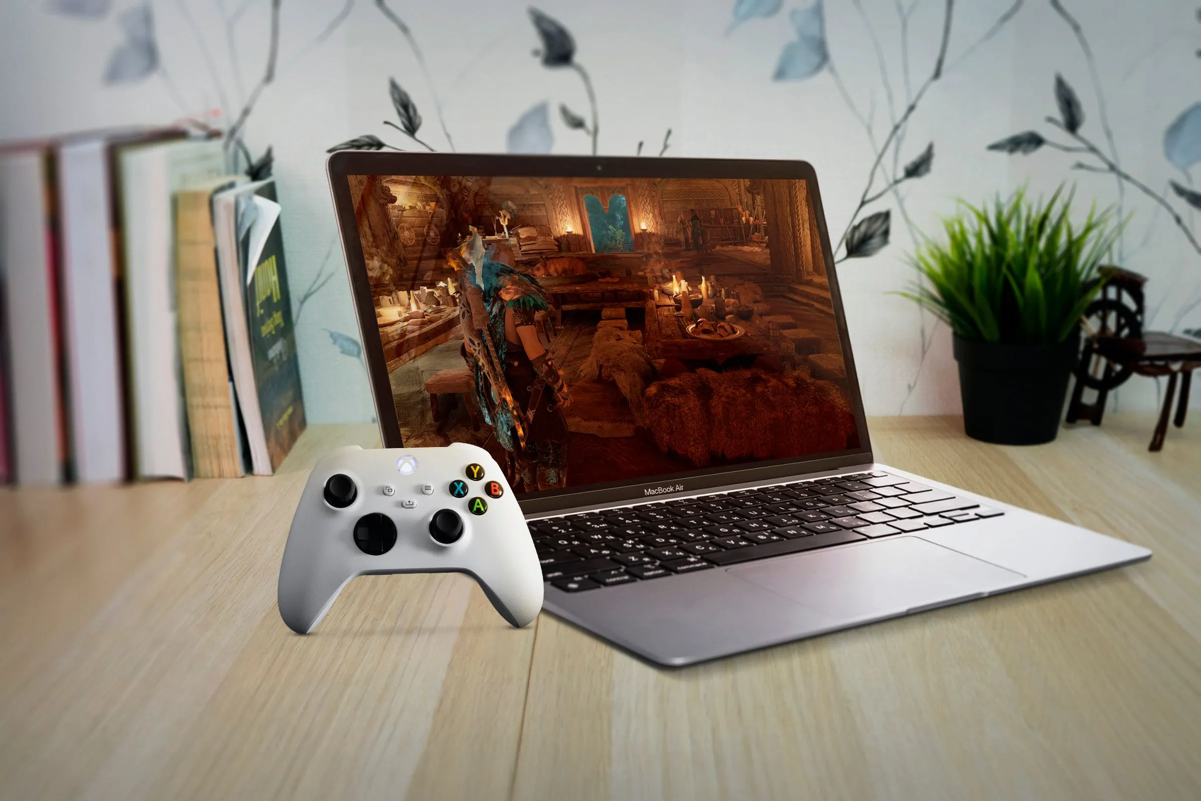 Một chiếc MacBook Air dưới bàn gỗ, màn hình hiển thị game cùng tay cầm Xbox, biểu trưng cho trải nghiệm game trên Mac