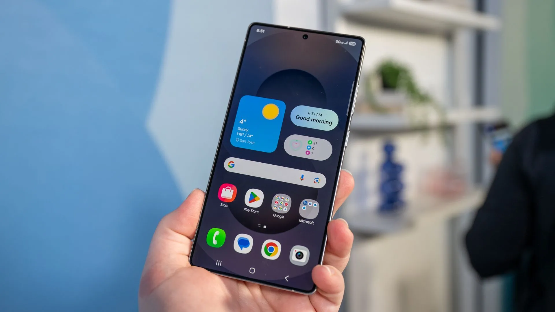 Một người đang cầm điện thoại Samsung Galaxy S25 Ultra, xem màn hình hiển thị tính năng One UI 8 và Android 16.