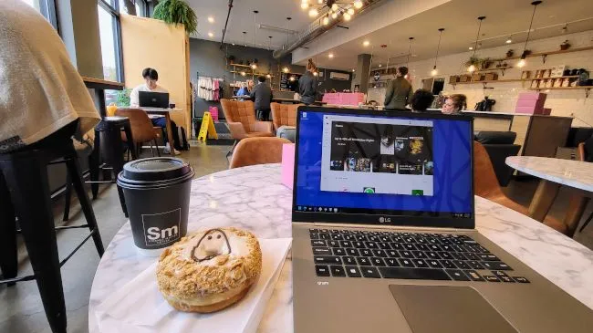 Một người đang làm việc với máy tính xách tay tại quán cà phê, tận dụng Wi-Fi công cộng
