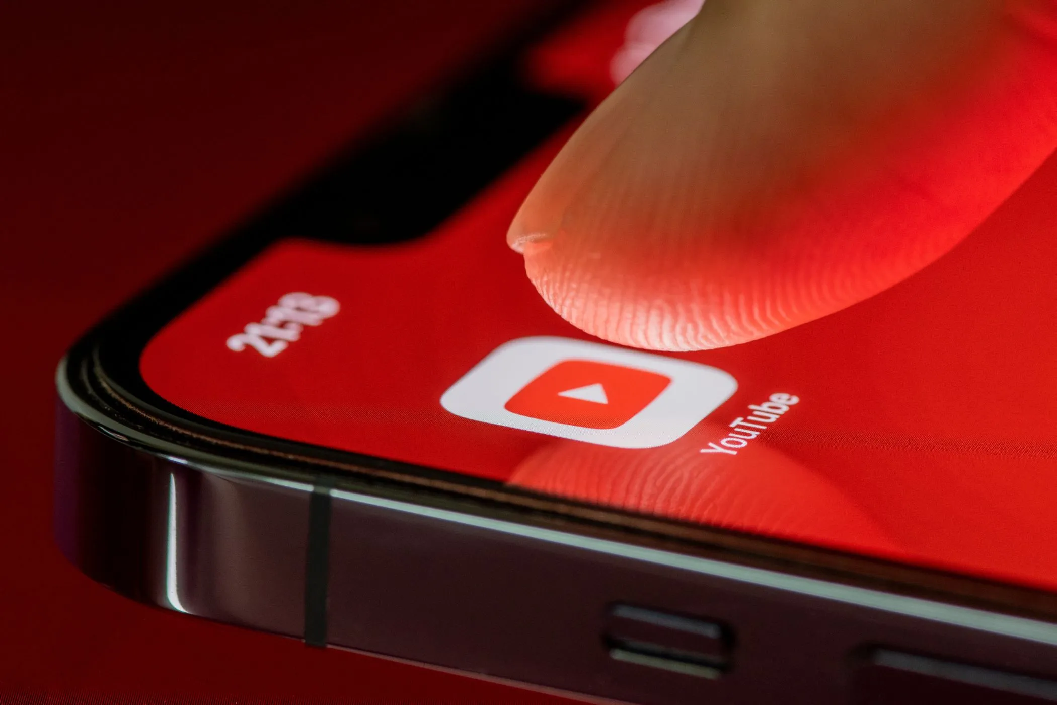Người dùng đang chạm vào biểu tượng ứng dụng YouTube trên màn hình điện thoại iPhone, minh họa việc truy cập ứng dụng.