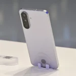 Samsung Galaxy A56 màu hồng đào đặt trên giá đỡ, mặt lưng kính và cụm camera nổi bật, thể hiện thiết kế cao cấp của điện thoại tầm trung này.