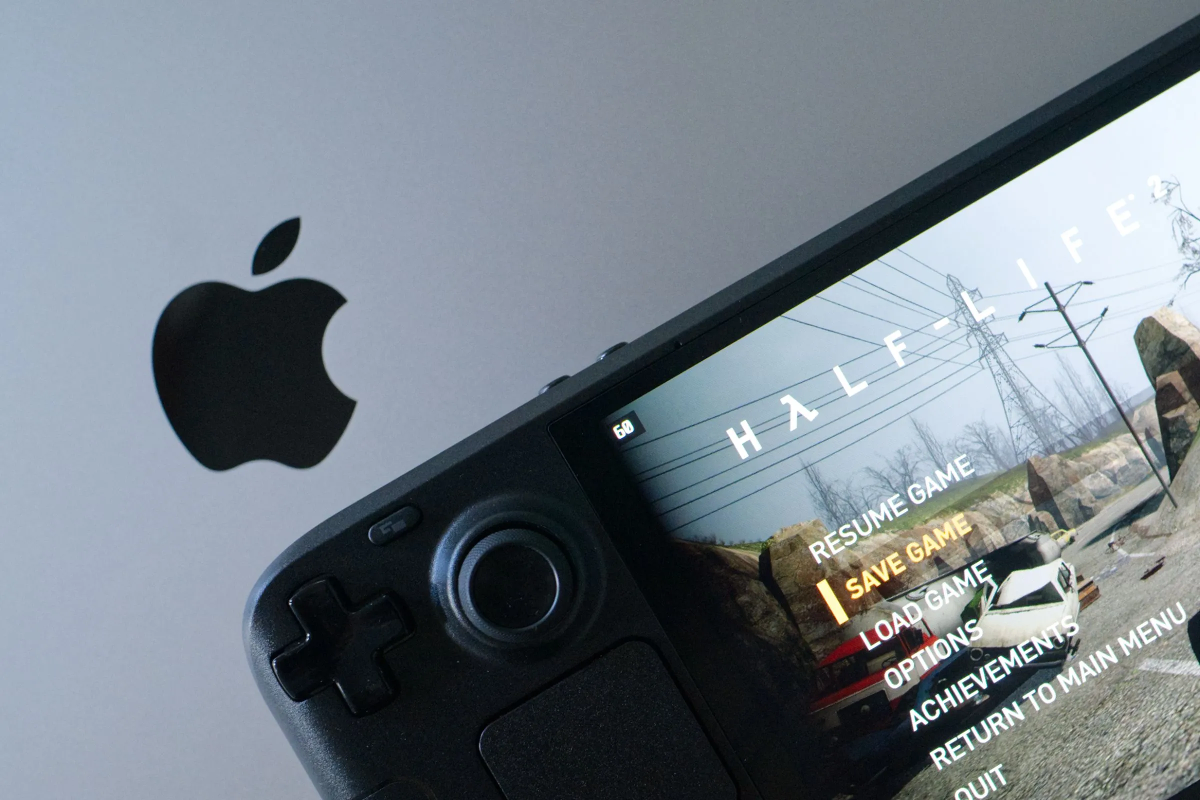Steam Deck OLED đang chơi Half-Life 2, đặt trên MacBook Pro, biểu tượng cho giá trị và sự phổ biến của thiết bị cầm tay của Valve.