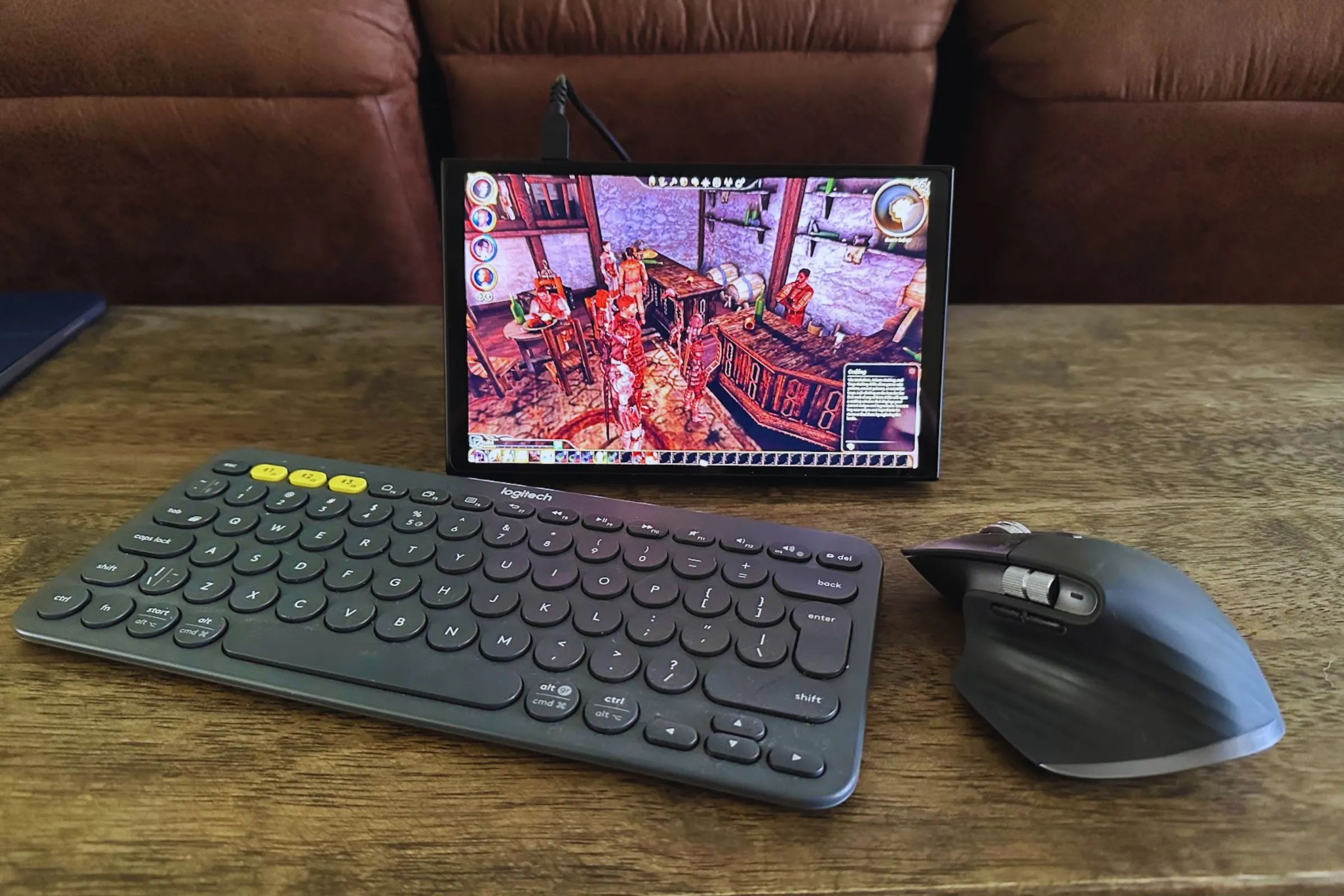 Bàn phím Logitech K380, chuột MX Master 3S và thiết bị cầm tay Lenovo Legion Go trên bàn gỗ, minh họa kết nối ngoại vi cho PC cầm tay.