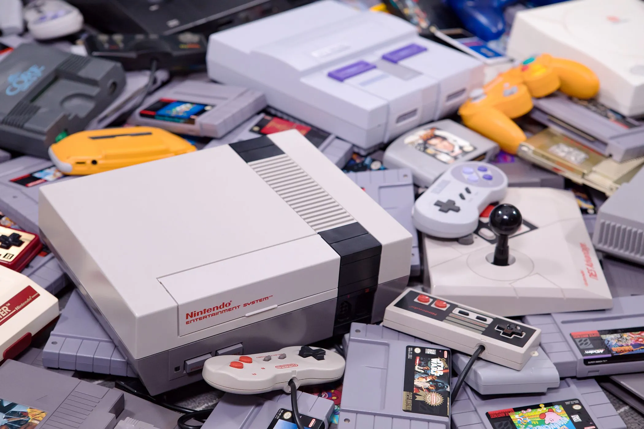 Bộ đôi console game NES và SNES cổ điển cùng băng game và tay cầm, gợi nhớ lịch sử phát triển của các thế hệ console.