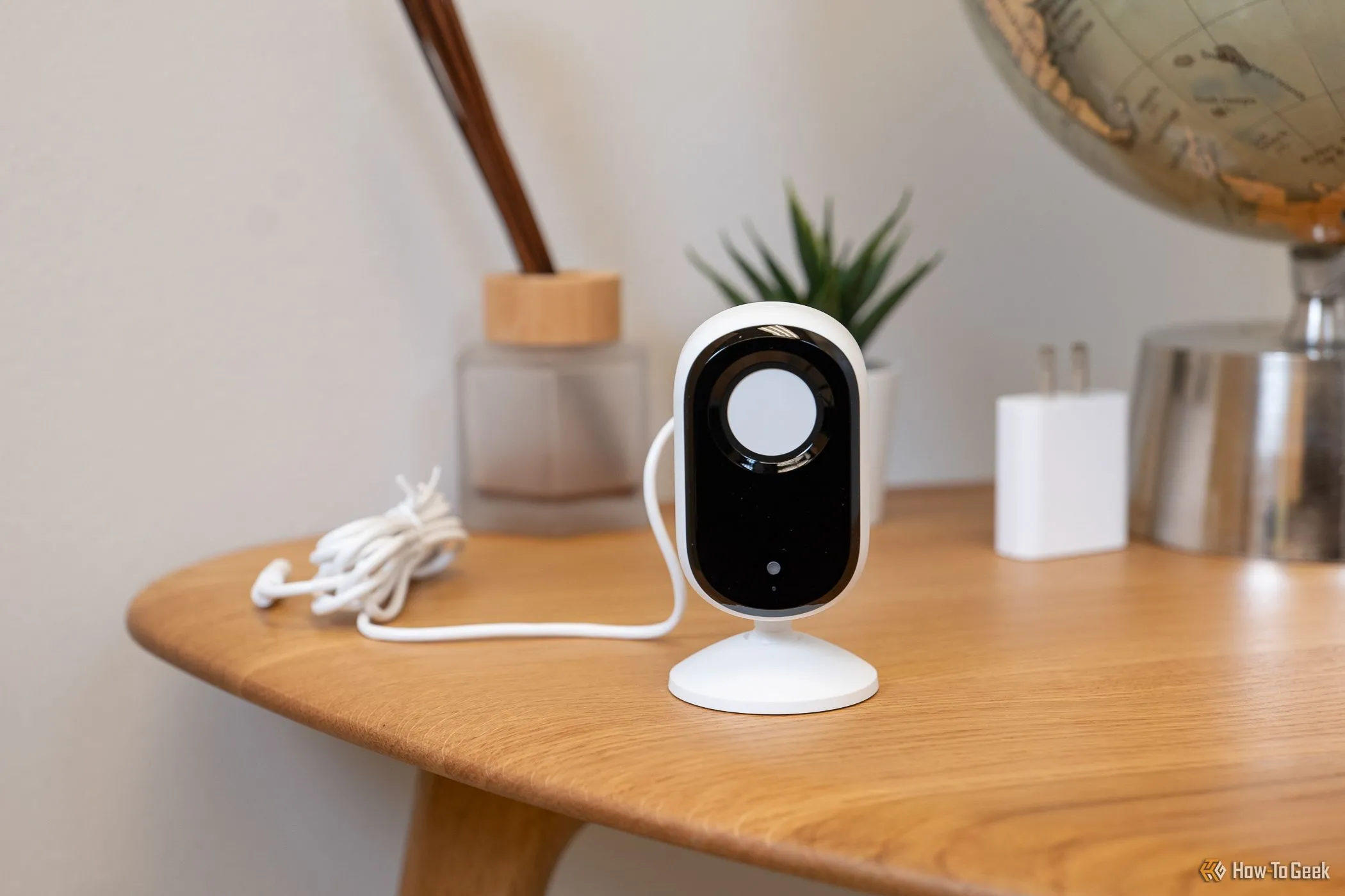 Camera an ninh trong nhà Arlo Essential Indoor Cam (2K) với nắp che riêng tư đang đóng, đặt trên bàn.