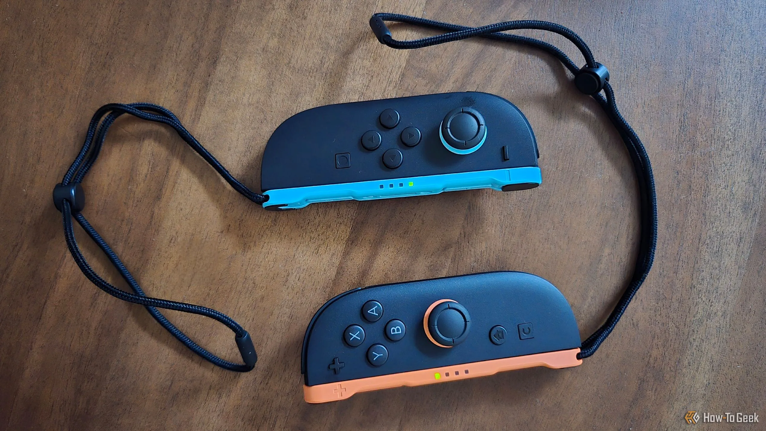 Cặp tay cầm Joy-Con 2 mới trên bàn cùng dây đeo cổ tay, thể hiện thiết kế cải tiến của Switch 2.