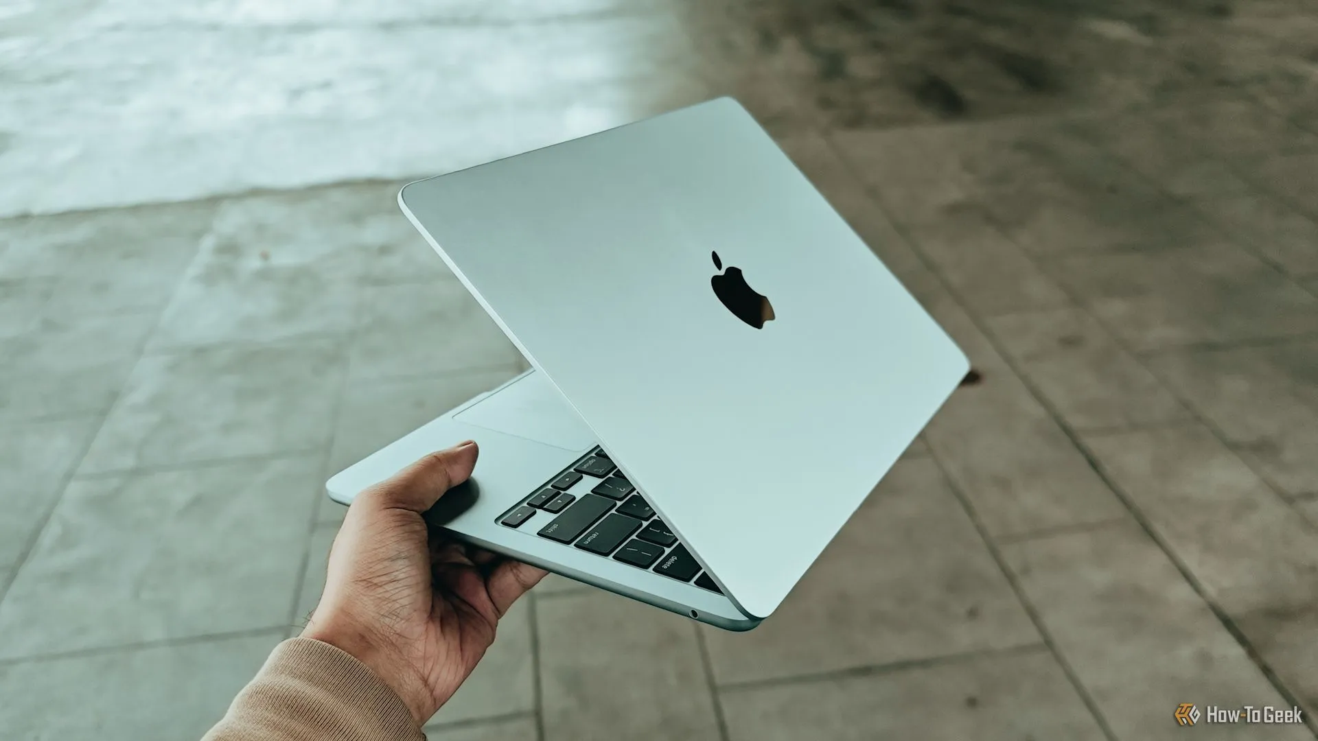 Chiếc MacBook Air M4 màu bạc được cầm trên tay, minh họa tính di động cao và nhu cầu kết nối mạng không dây ổn định cho laptop Apple.