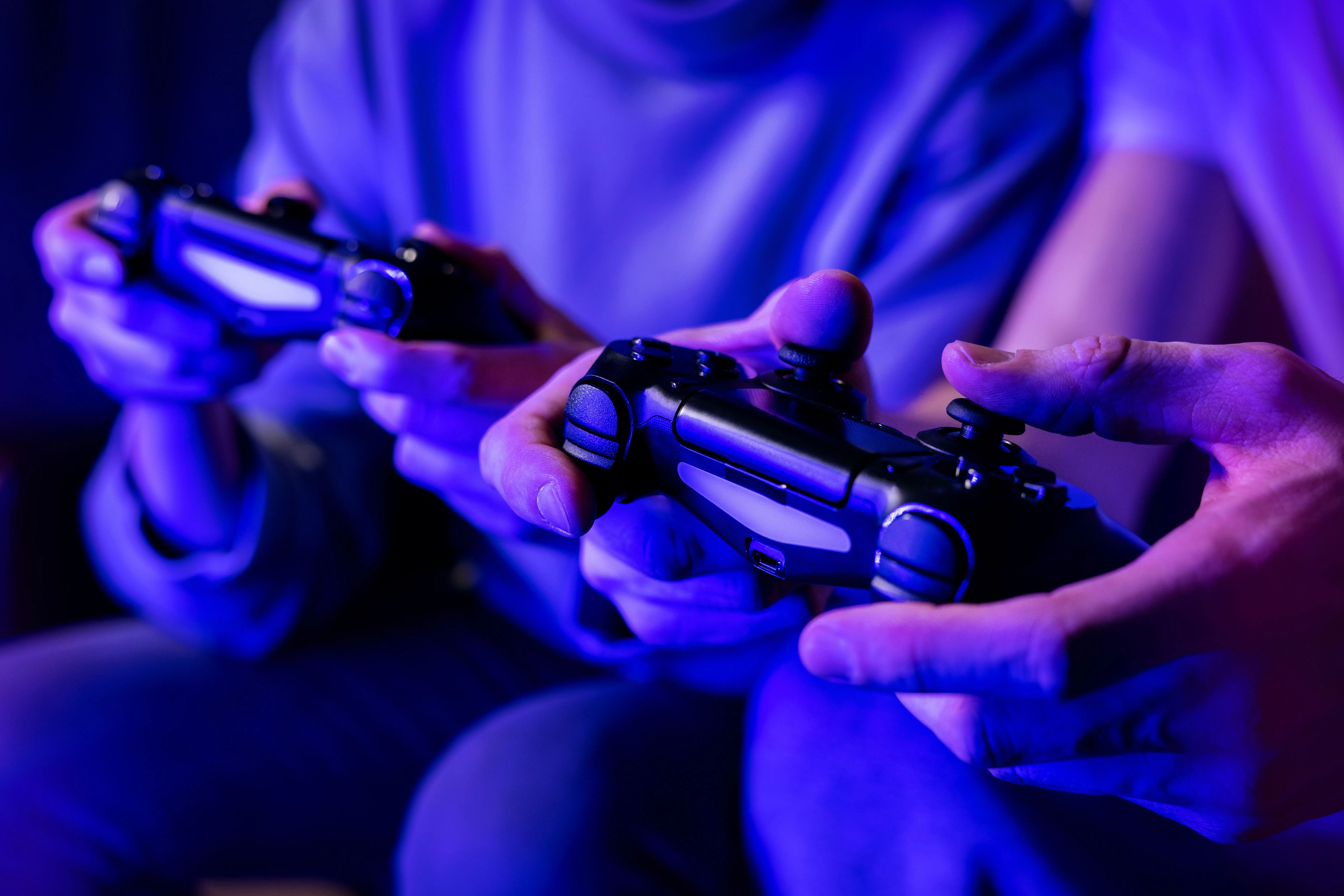 Hai người bạn cùng chơi game online nhiều người trên sofa, thể hiện nhu cầu về một gói PlayStation Plus chỉ dành cho multiplayer.