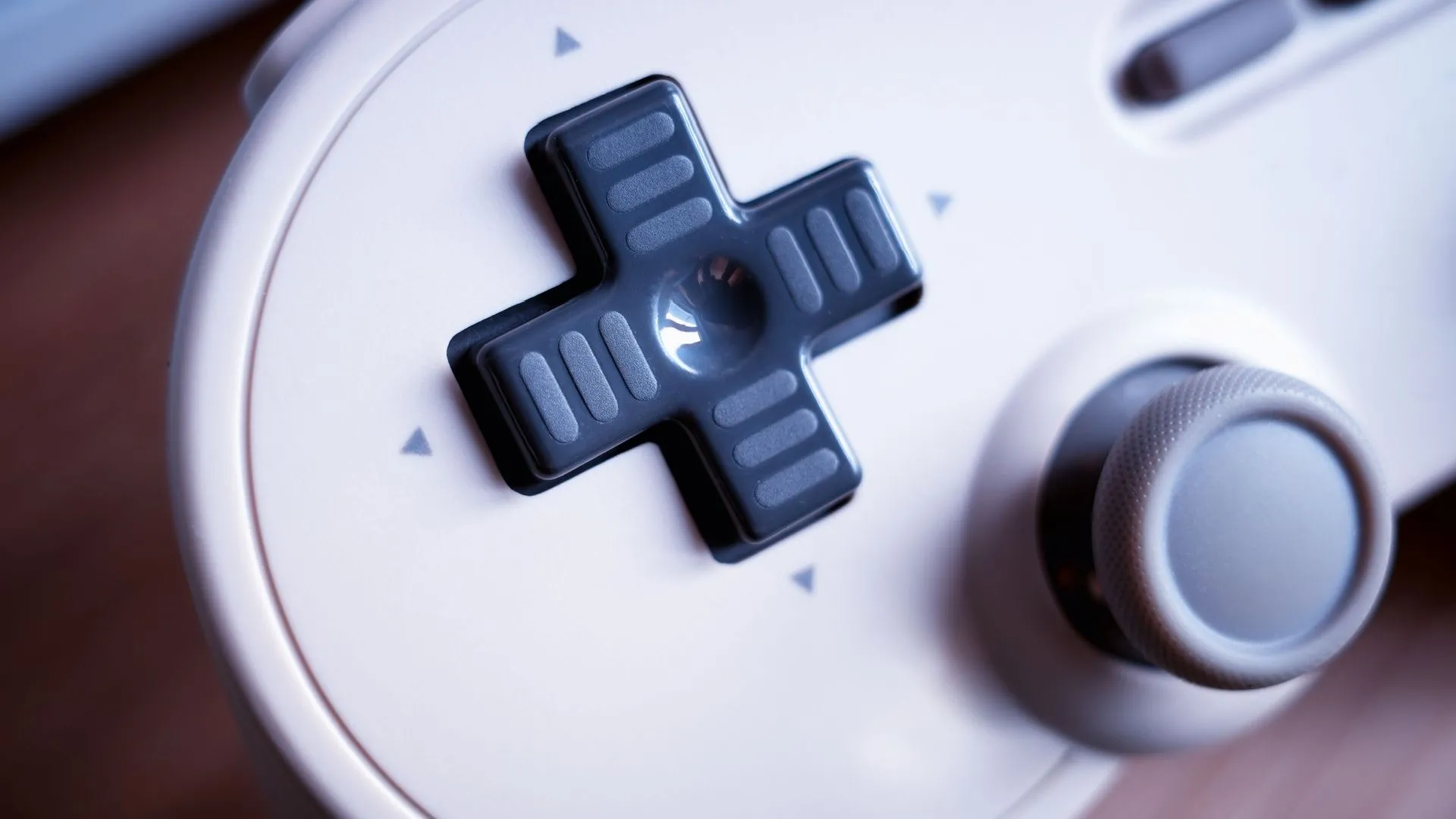 Hình ảnh cận cảnh tay cầm chơi game với D-pad cổ điển trên nền mờ