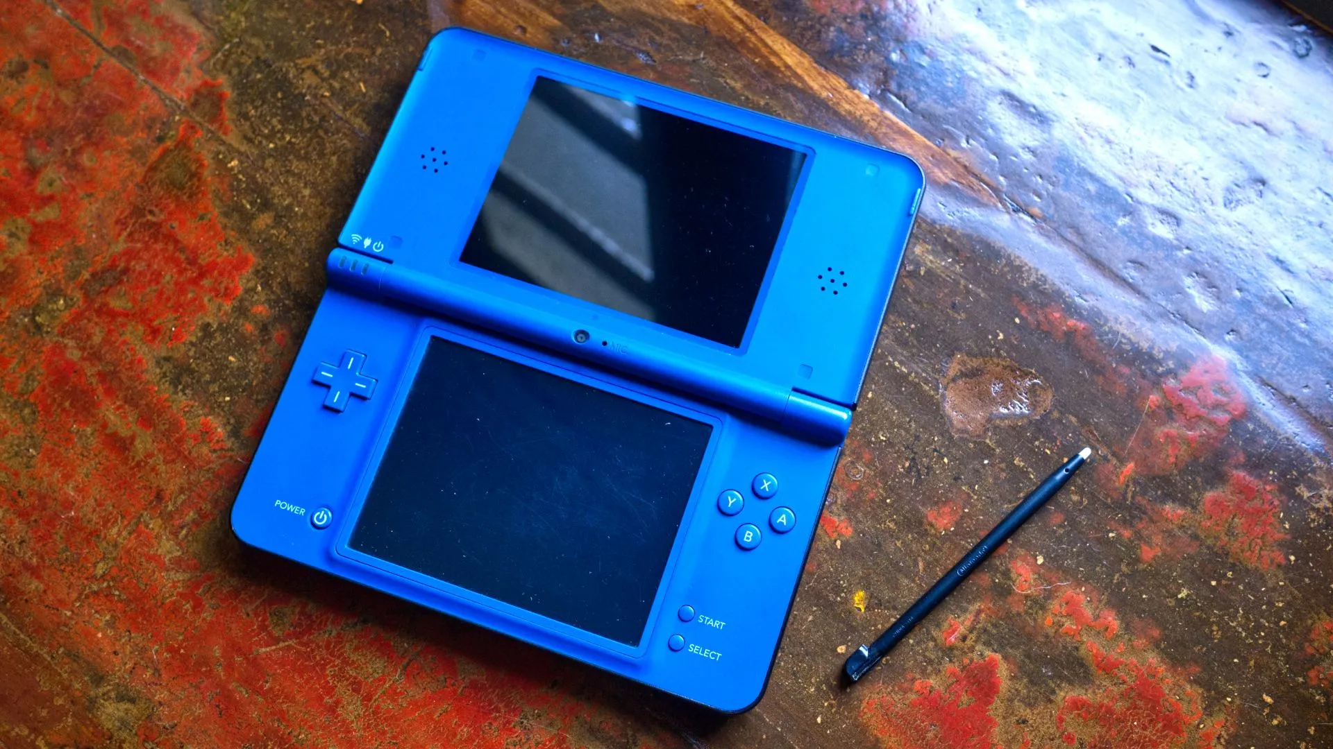 Hình ảnh chiếc Nintendo DSi XL màu xanh lam đang mở cùng với bút stylus