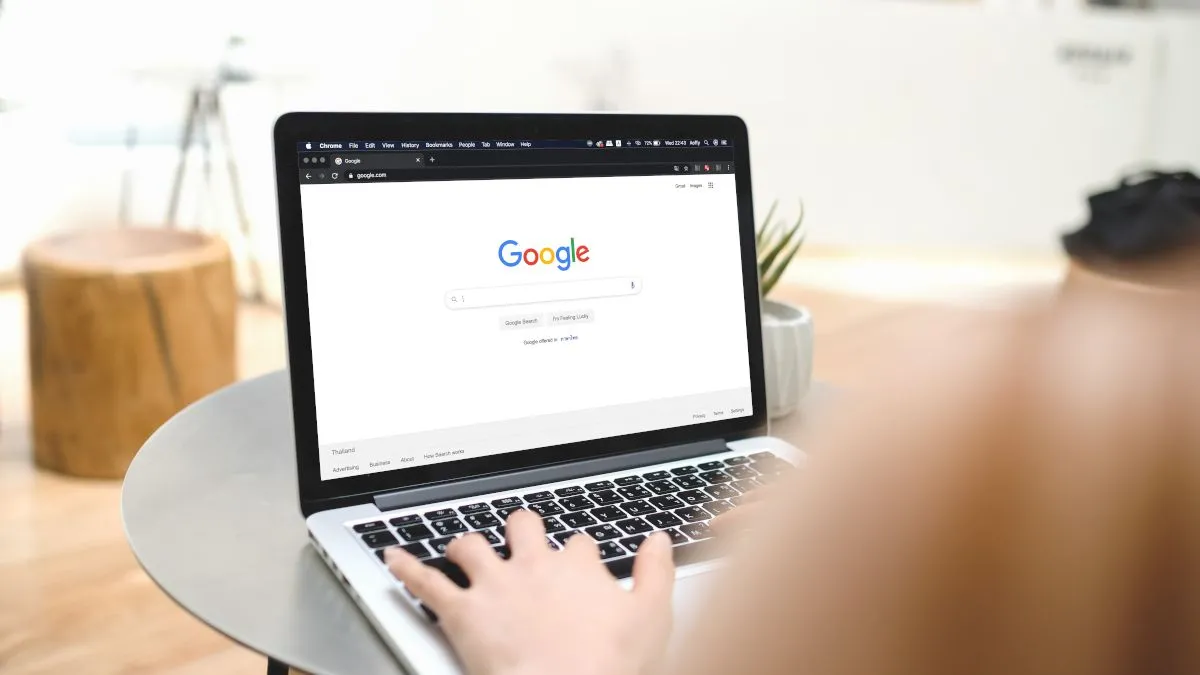 Hình ảnh một người phụ nữ đang gõ bàn phím laptop với trang Google Search mở trên trình duyệt, minh họa việc sử dụng công cụ tìm kiếm