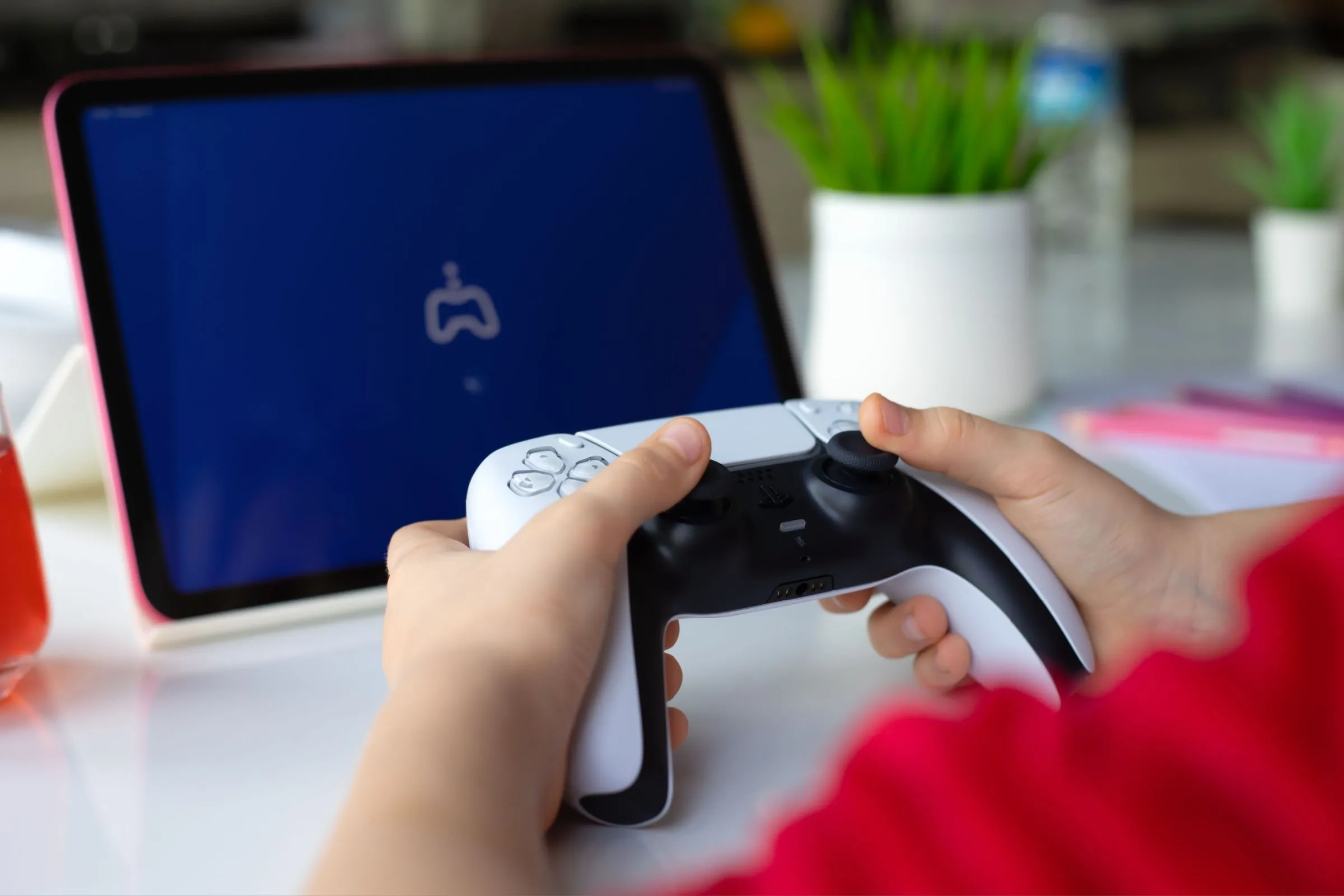 Hình ảnh trẻ em sử dụng tay cầm DualSense và iPad Air, minh họa khả năng chơi game PS5 di động thông qua Remote Play.