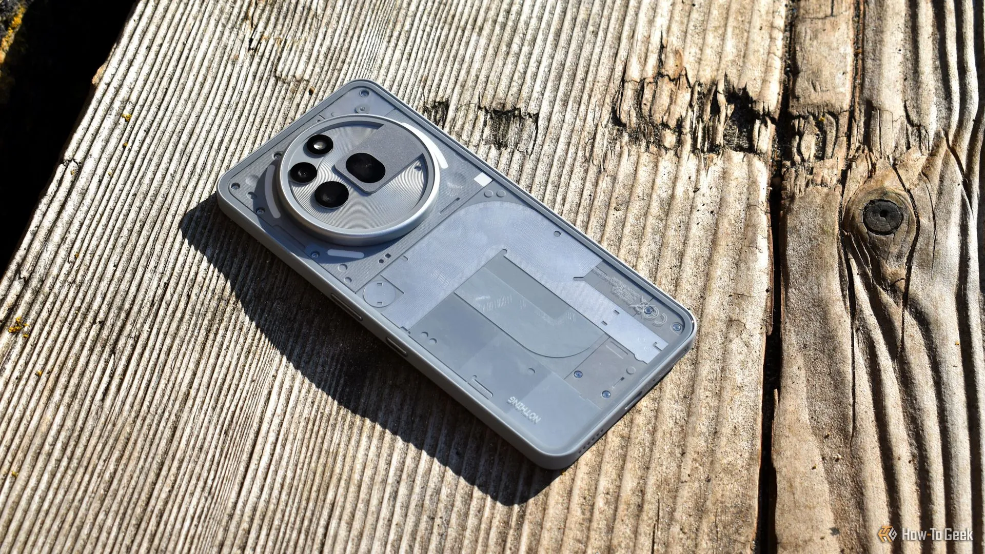 Mặt lưng Nothing Phone (3a) Pro nhìn từ trên xuống trong không gian ngoài trời, nổi bật cụm camera và họa tiết