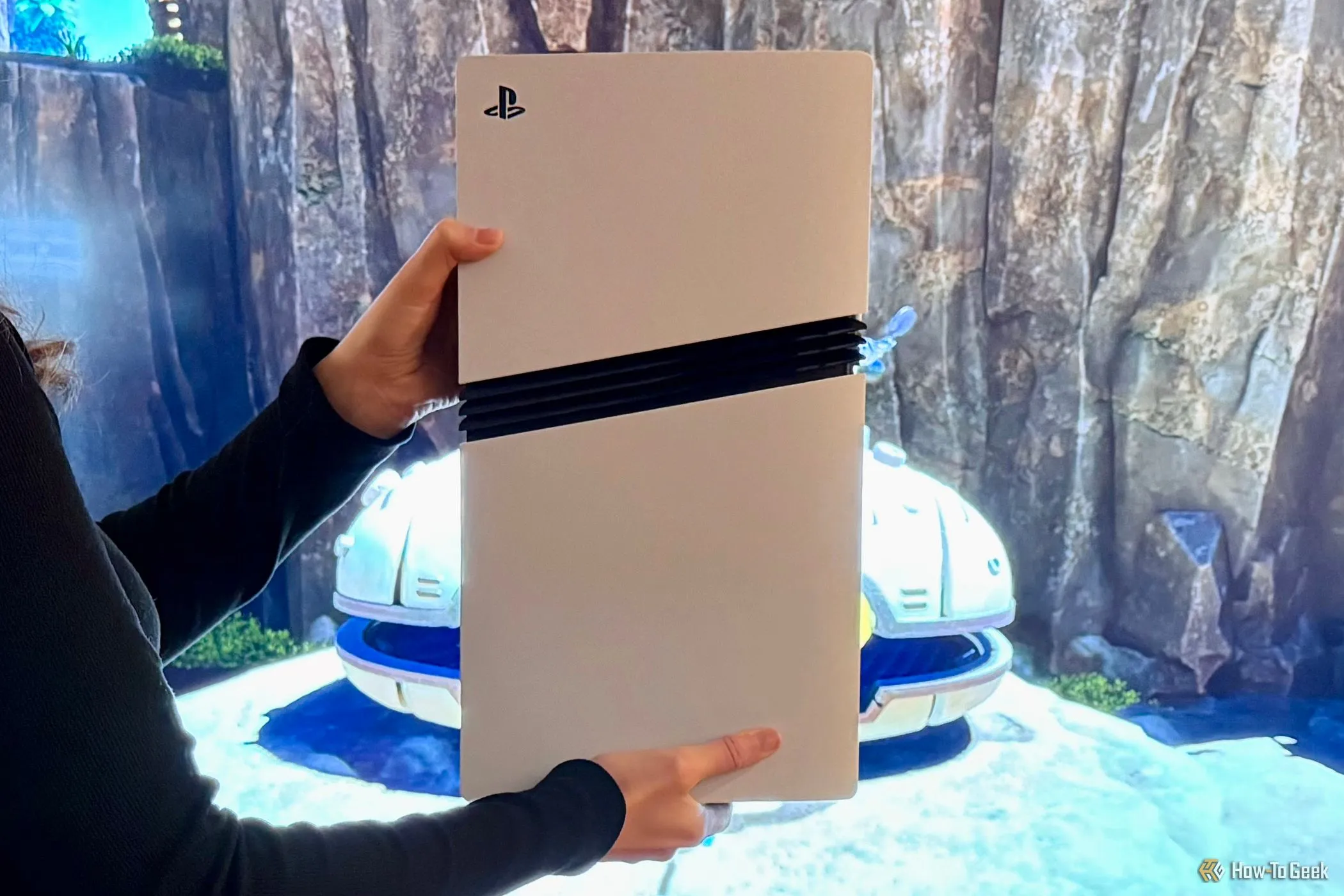 Máy chơi game Sony PlayStation 5 Pro màu trắng được cầm trước màn hình TV đang hiển thị hình ảnh game