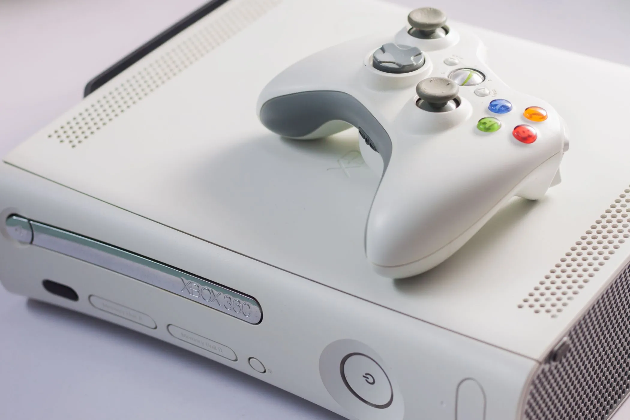 Máy chơi game Xbox 360 màu trắng cùng bộ điều khiển không dây, biểu tượng Xbox sáng