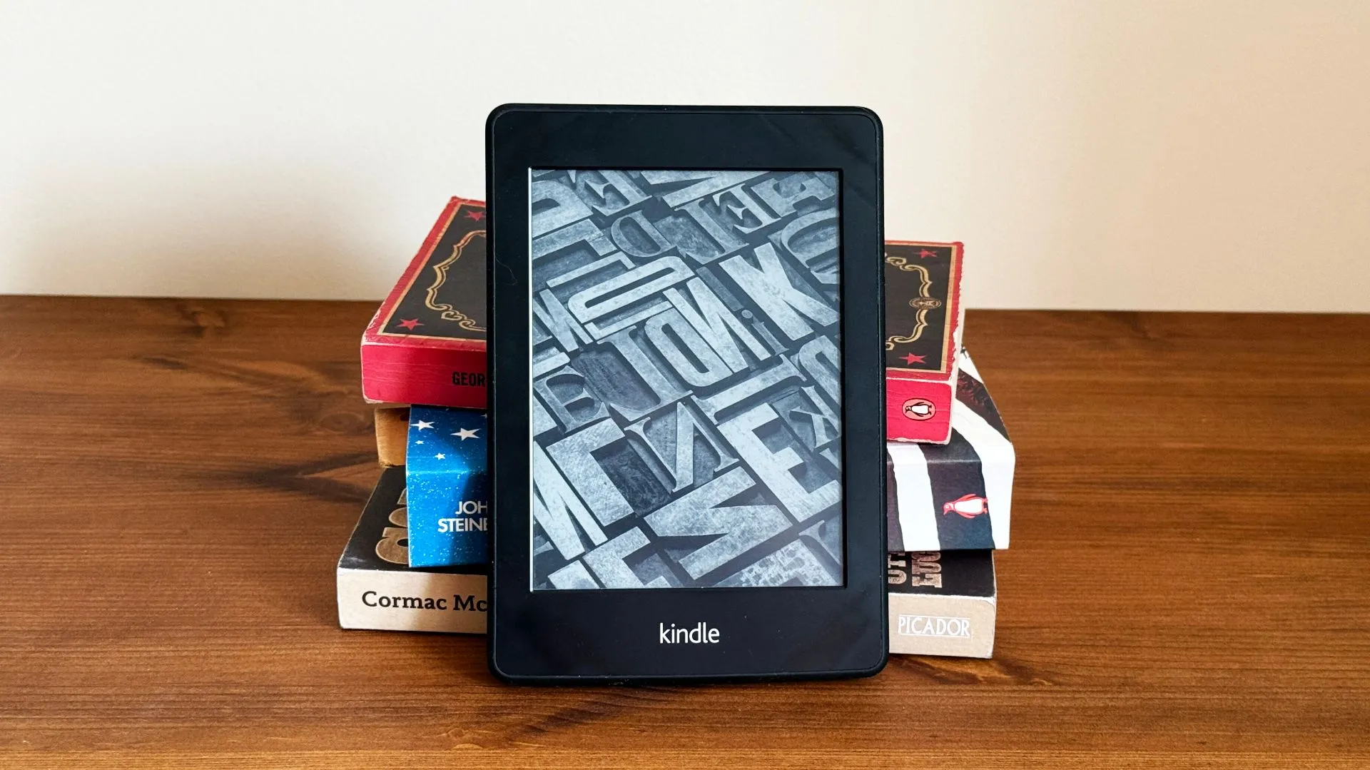 Máy đọc sách Kindle nằm phía trước chồng sách giấy truyền thống