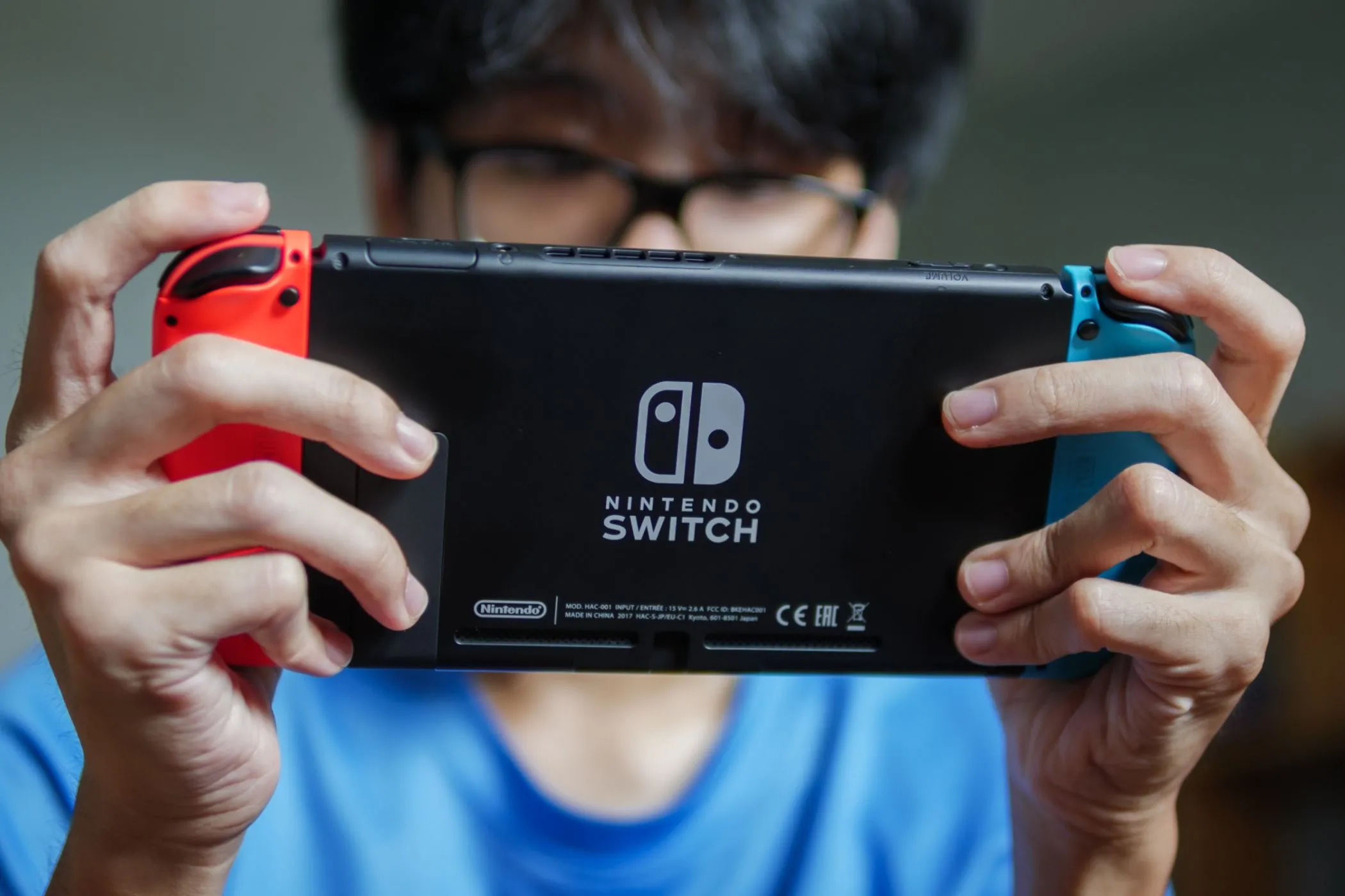 Một người đàn ông đang chơi game trên Nintendo Switch ở chế độ cầm tay, biểu tượng của sự tiện lợi khi chơi game linh hoạt.