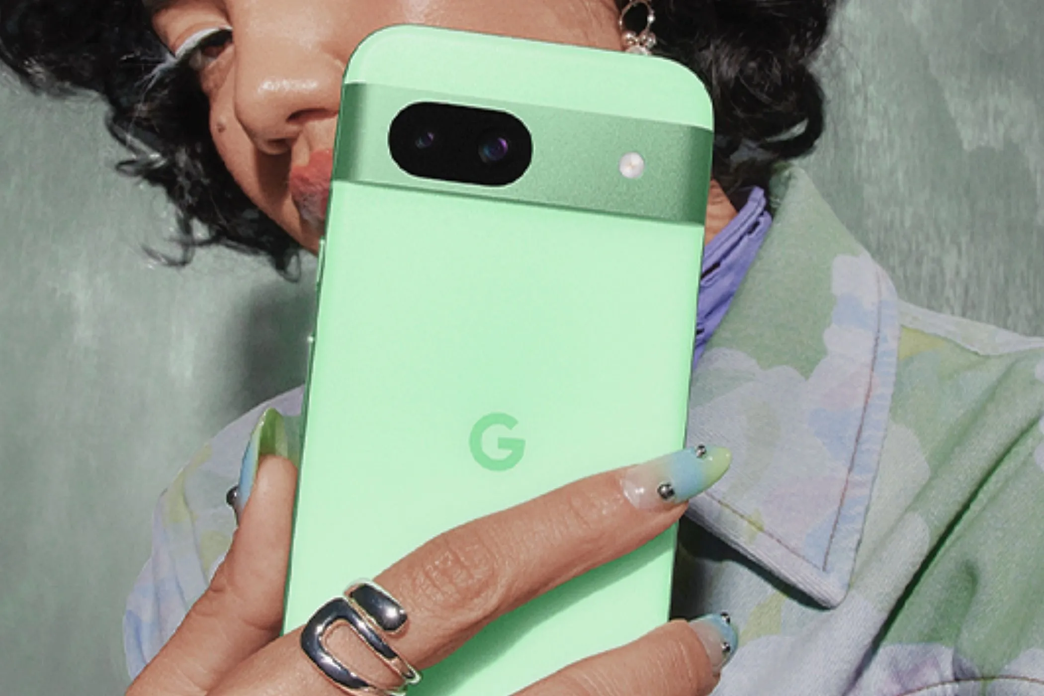 Một phụ nữ đang cầm chiếc Google Pixel 8a màu xanh Aloe, thể hiện thiết kế của máy