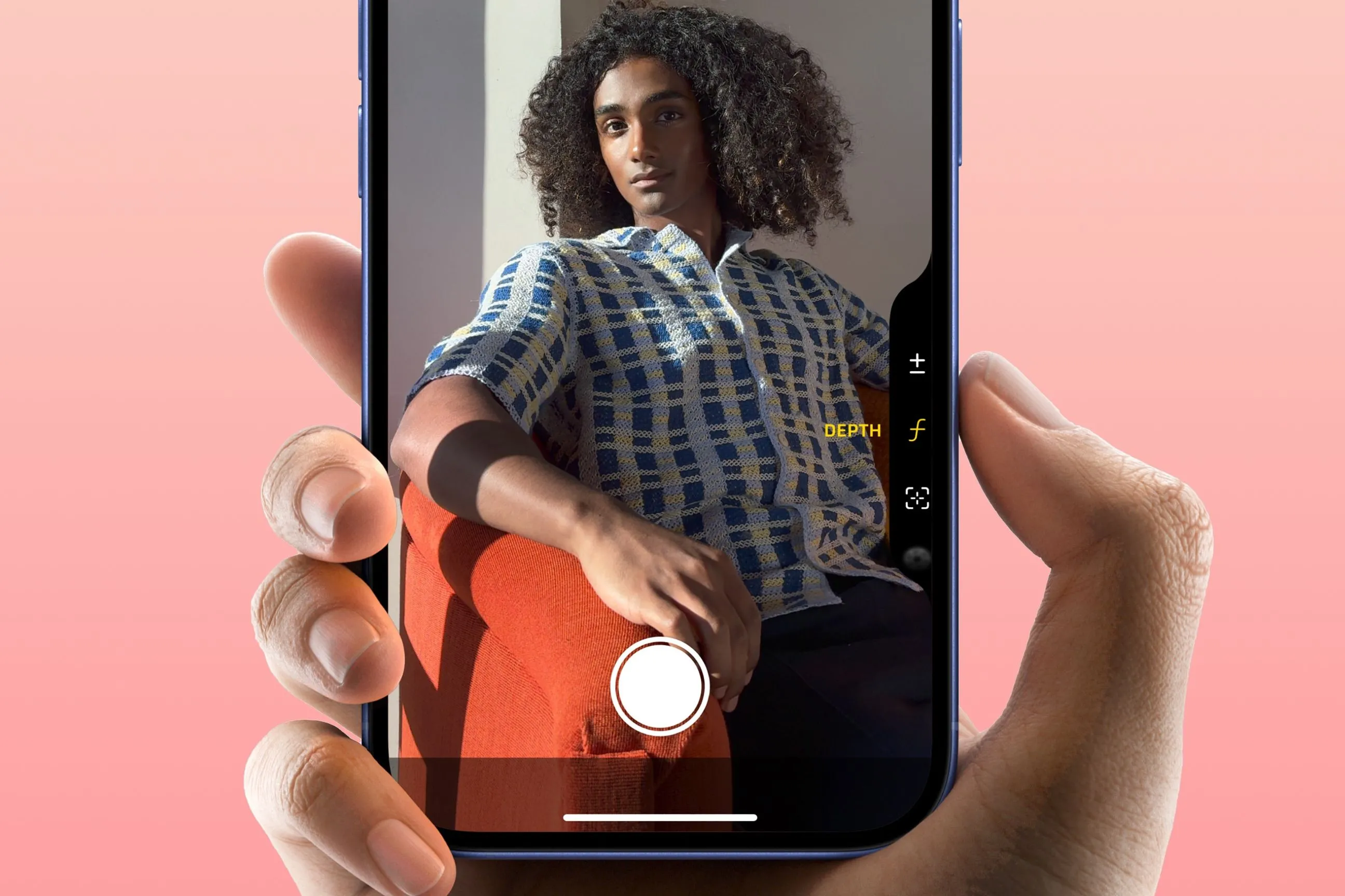 Ngón tay trỏ nhấn nút Camera Control trên iPhone 16 khi chụp ảnh