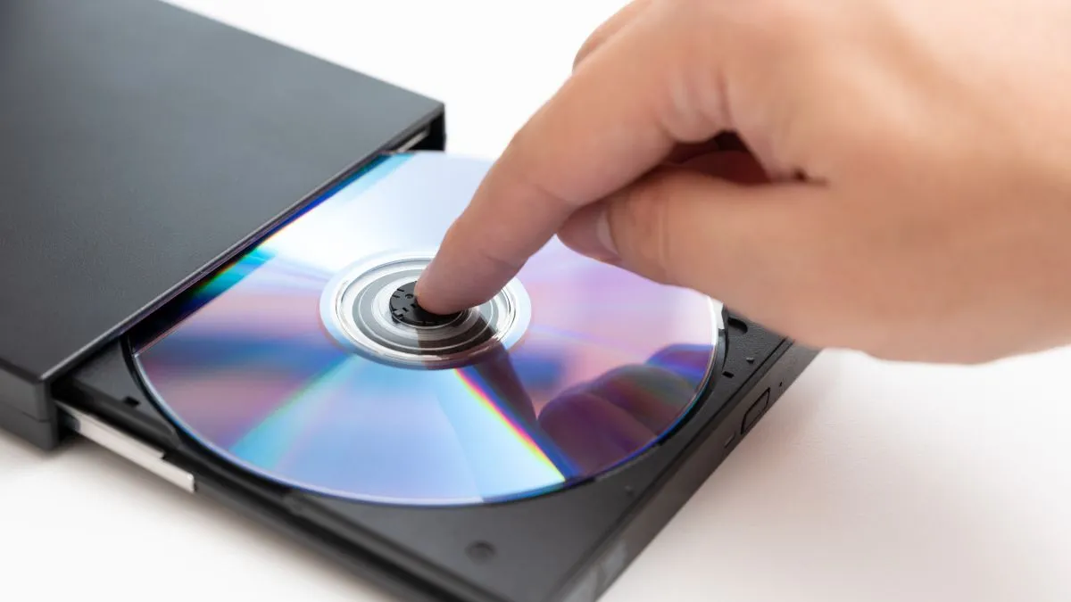 Người đang cầm một đĩa DVD trong tay, minh họa cho việc sử dụng ổ đĩa quang