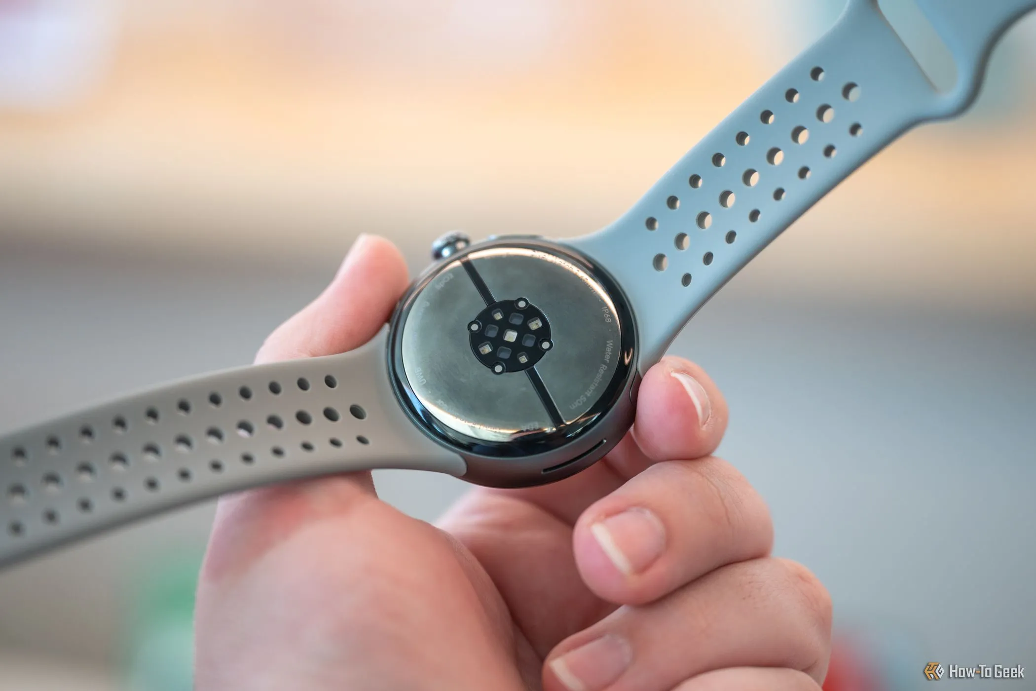 Người dùng cầm Google Pixel Watch 3 hiển thị cảm biến mặt dưới
