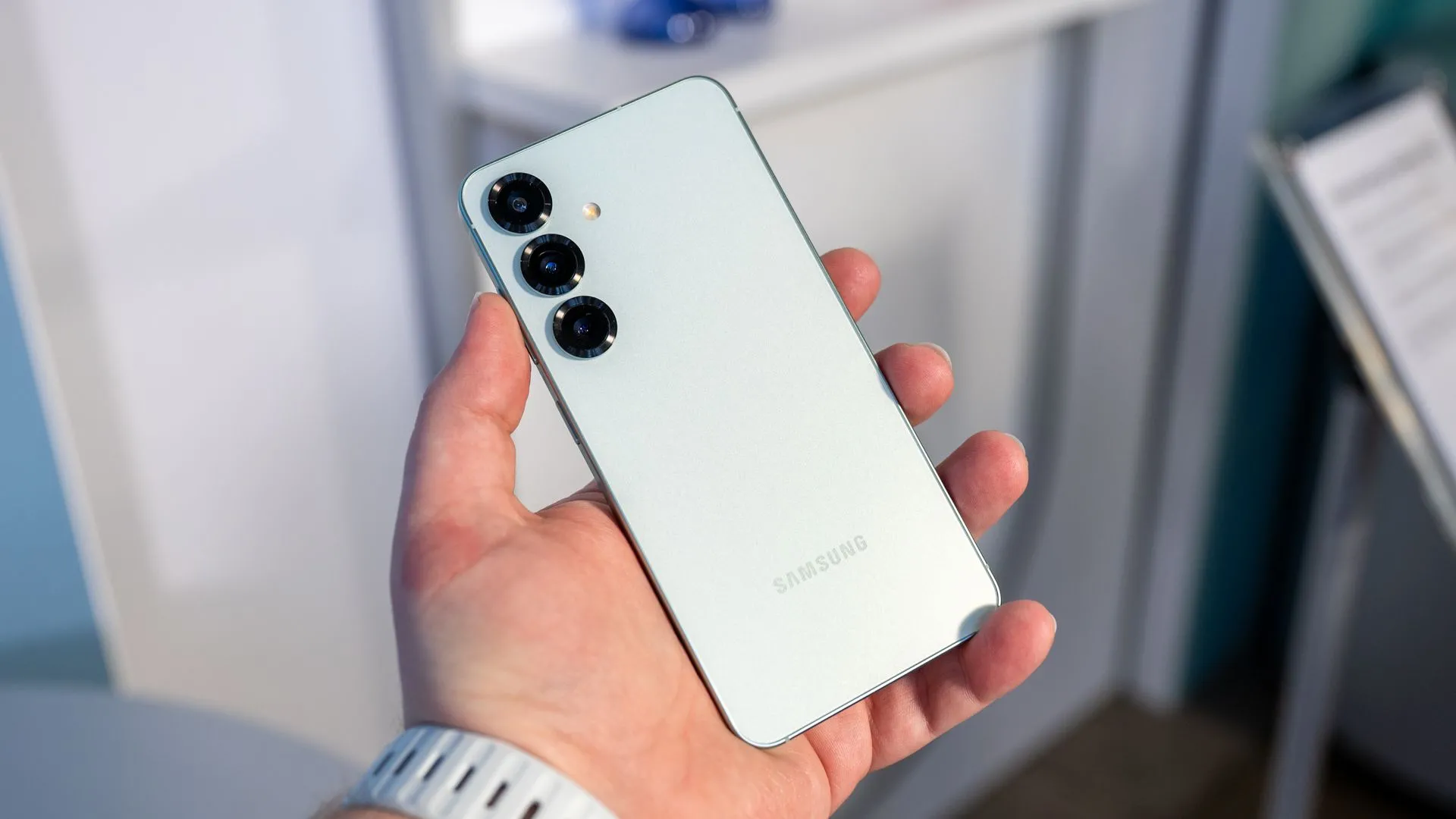 Người dùng cầm Samsung Galaxy S25 và nhìn vào cụm camera sau, nhấn mạnh tính năng chụp ảnh và thiết kế của điện thoại.
