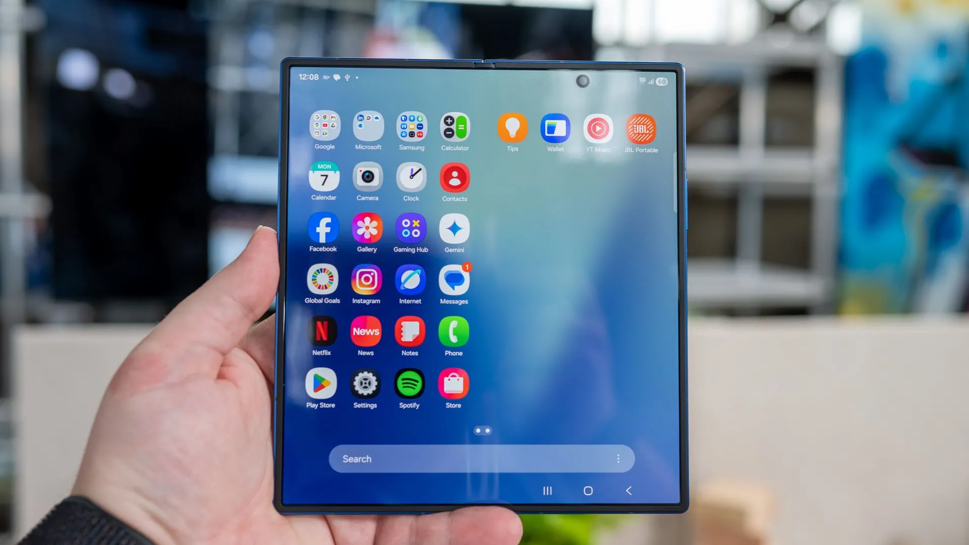 Người dùng cầm Samsung Galaxy Z Fold 7 mở ra, hiển thị khay ứng dụng trên màn hình bên trong với camera đục lỗ
