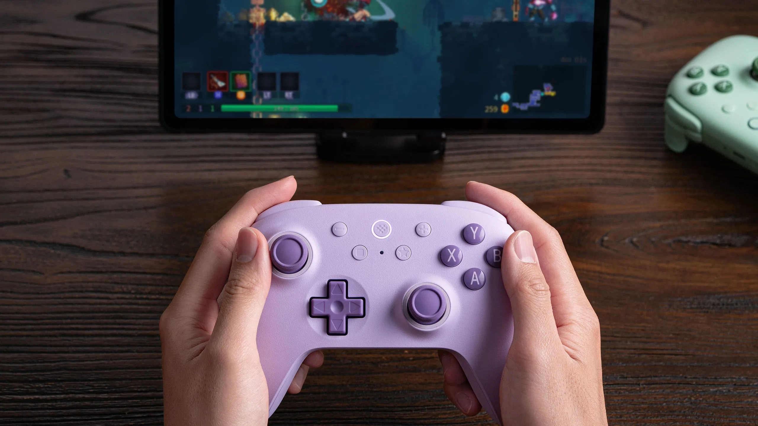 Người dùng cầm tay cầm 8BitDo Ultimate 2C Wireless chơi game Dead Cells trên máy tính bảng, minh họa tính di động và thoải mái.
