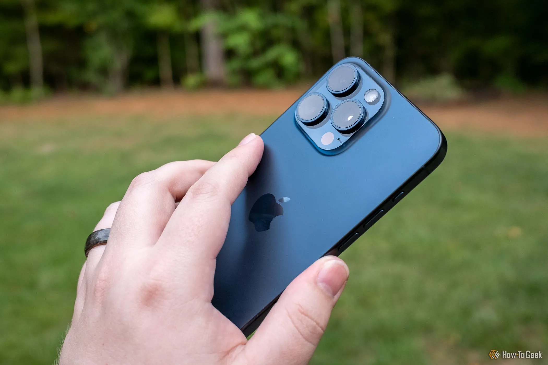 Người dùng đang chạm vào mặt lưng của iPhone 15 Pro Max để kích hoạt cử chỉ Back Tap