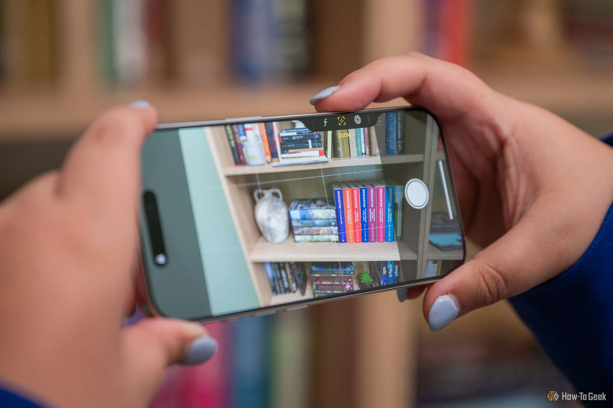 Người dùng điều chỉnh zoom bằng nút Camera Control trên iPhone 16 Pro khi cầm ngang