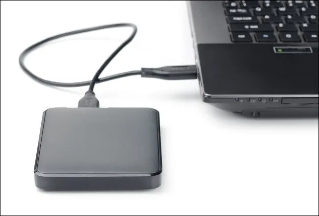Ổ cứng di động gắn ngoài kết nối với laptop qua cáp USB, minh họa cho việc sử dụng thiết bị lưu trữ ngoài.