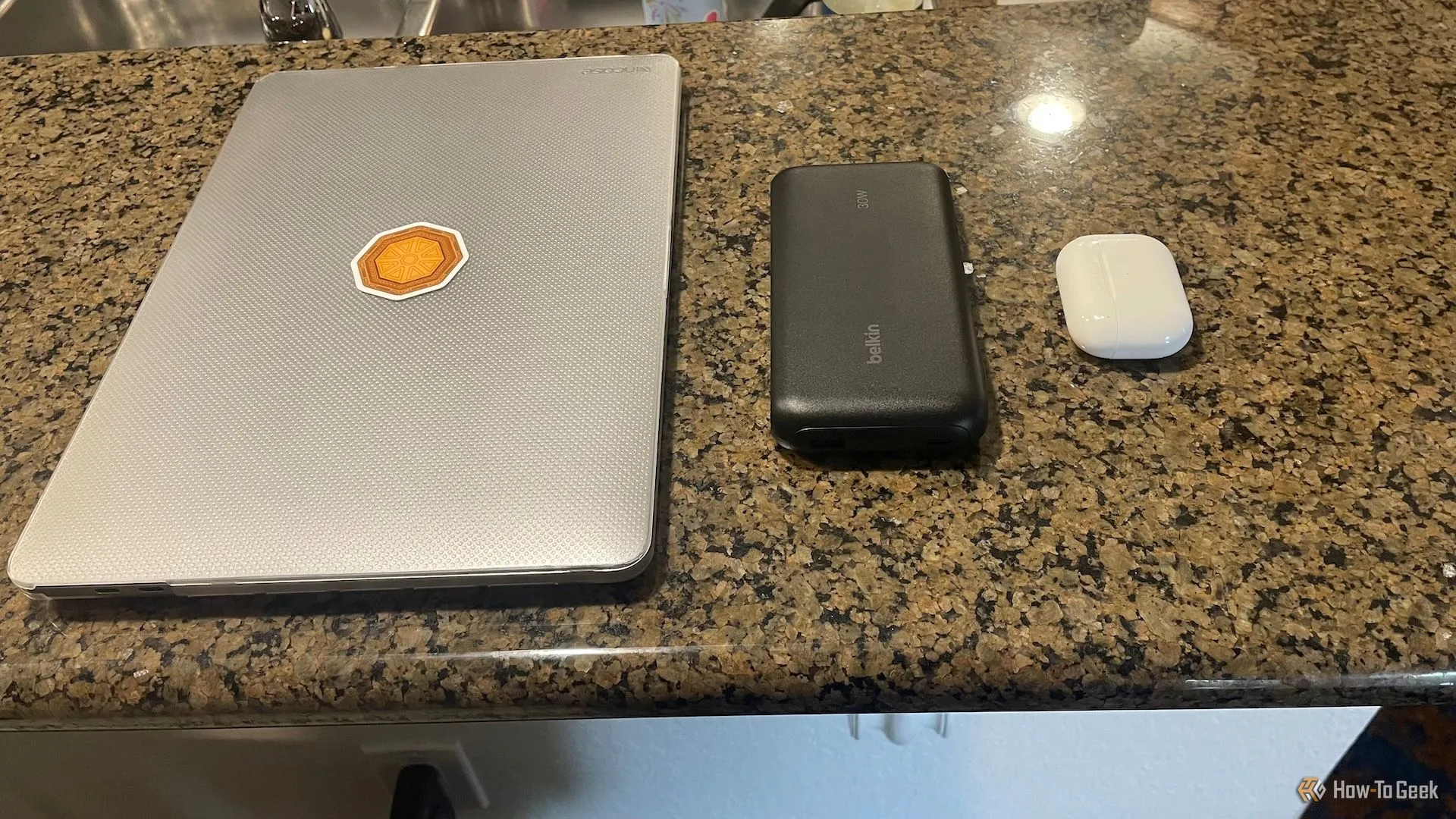 Pin sạc dự phòng Belkin BoostCharge 20K đặt cạnh MacBook Pro và hộp AirPods, cho thấy kích thước tương đối