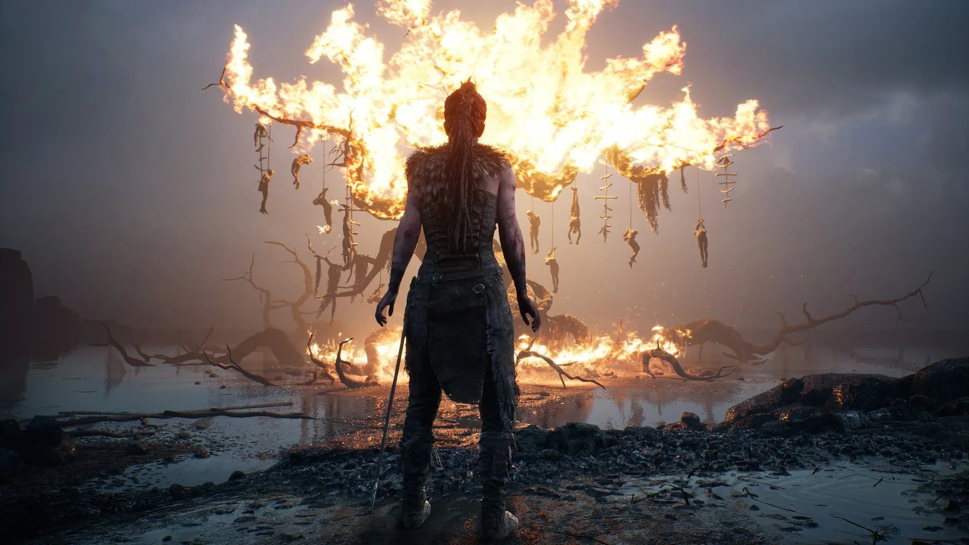 Senua nhìn một cái cây bốc cháy trong Hellblade: Senua’s Sacrifice, thể hiện hành trình đầy thử thách của cô trong thế giới thần thoại Bắc Âu.