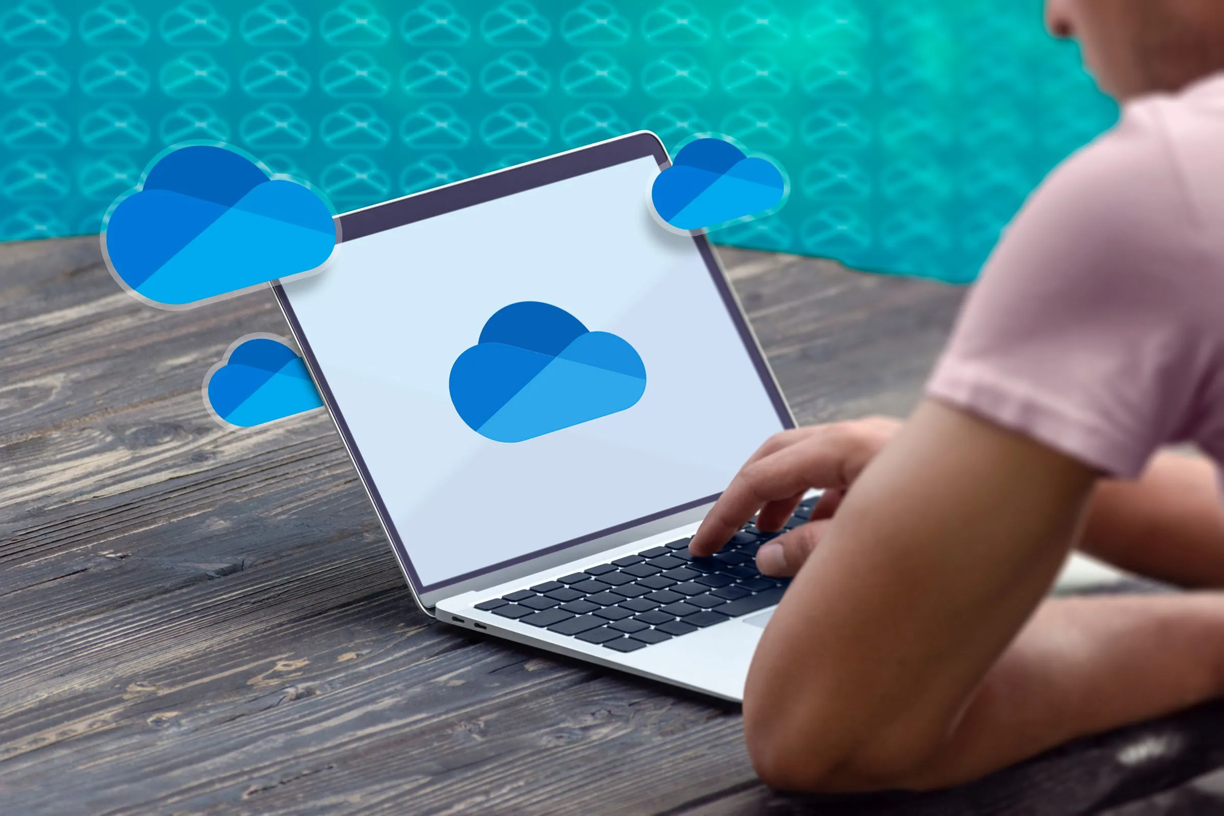 Một người đang sử dụng máy tính xách tay với logo OneDrive trên màn hình